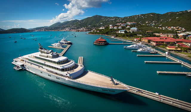 Un yacht amarré à un pont, sur une mer turquoise. 