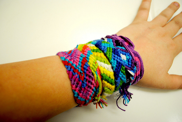 Photographie d'un avant bras couvert de bracelets brésiliens.