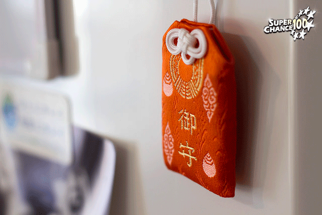 Photo d'une omamori attachée à un mur.