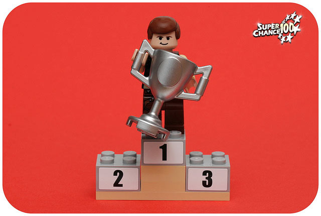 Photographie d'un personnage de lego tenant une coupe sur un podium.