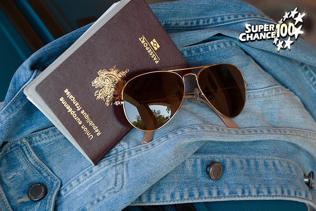 Passeport français et lunettes de soleil posés sur une veste en jean.