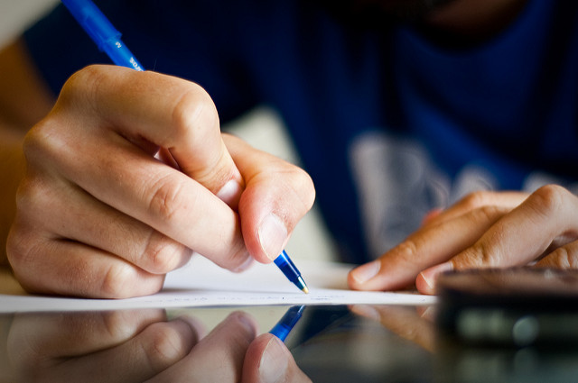 Personne en train d'écrire sur du papier.